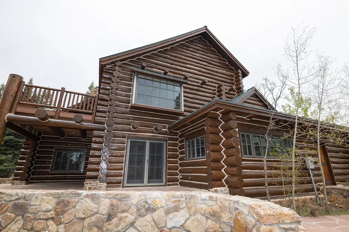 Professional log home restoration specialist performing precision sanding and finishing work on rustic mountain cabin logs