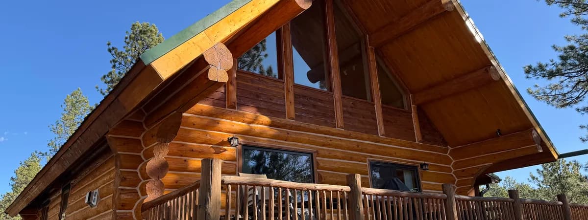Handcrafted log railing system on Colorado mountain cabin deck with pine trees and mountain backdrop