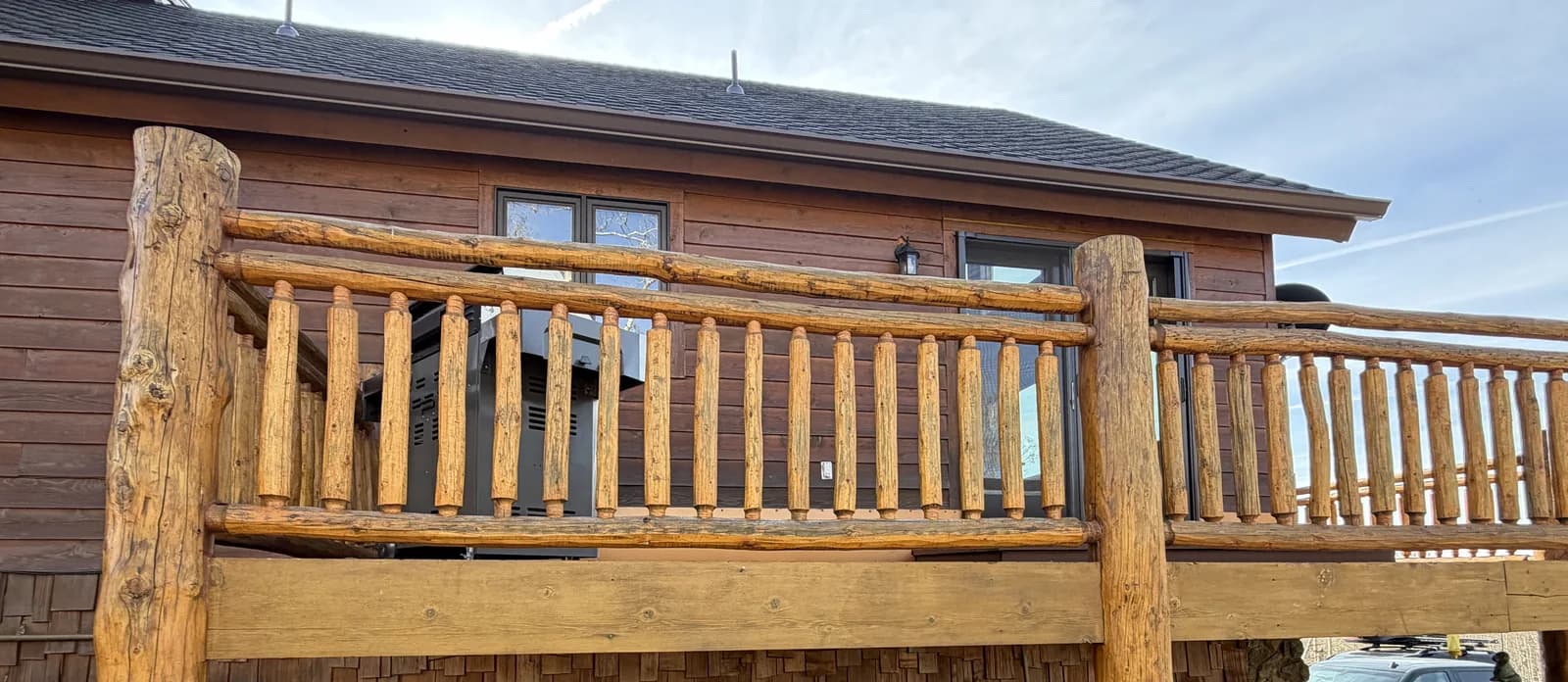 Log Deck & Railing System Freshly stained log home deck with a full log railing system and hand-peeled log posts against a Colorado log facade