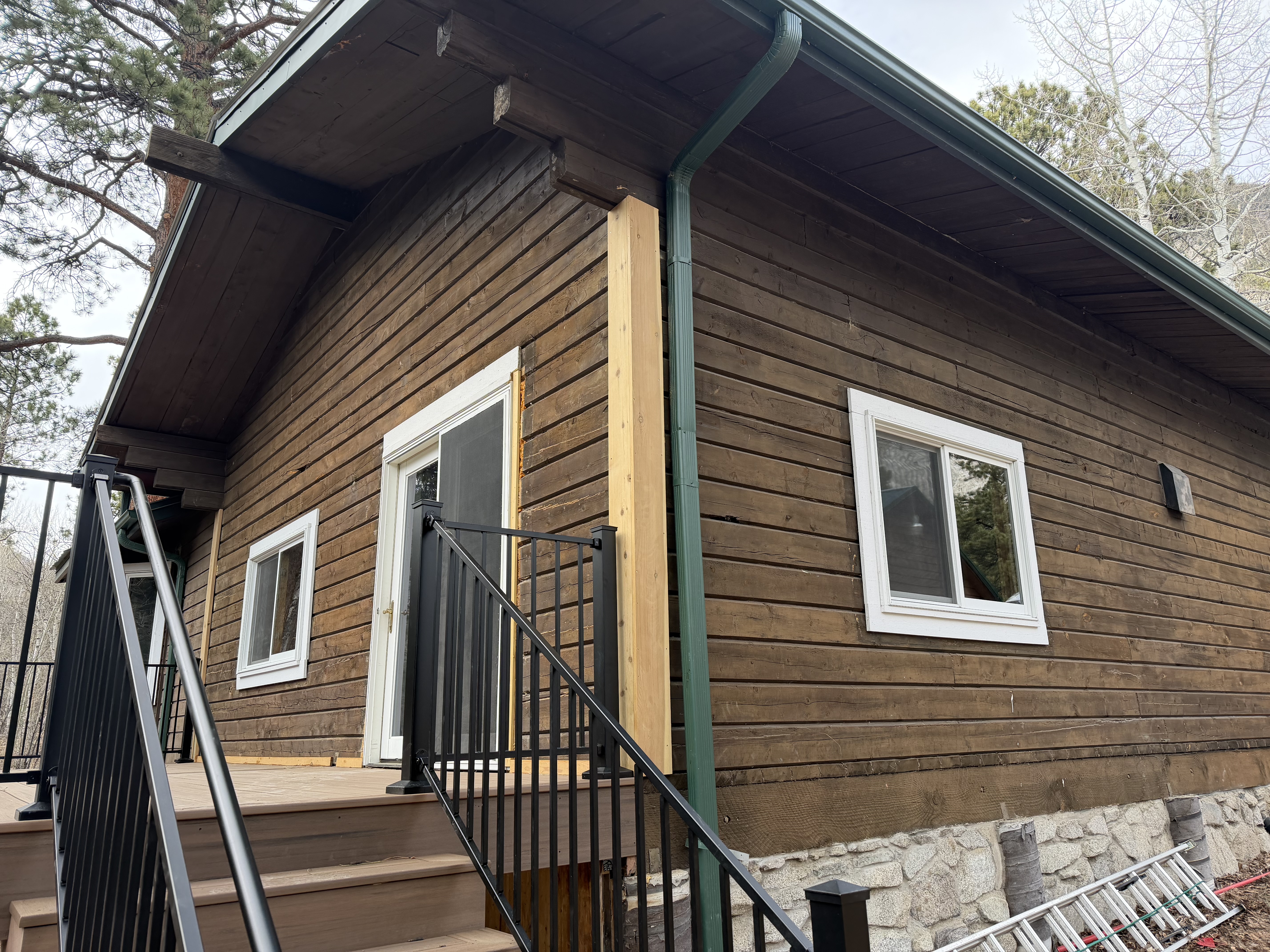 Log home in Nathrop Colorado before restoration showing old brown paint that was peeling and trapping moisture on the log walls
