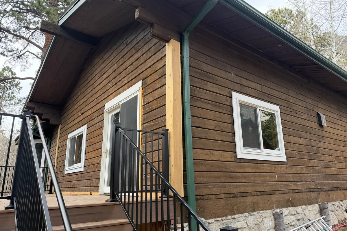 Log home in Nathrop Colorado before restoration showing old brown paint that was peeling and trapping moisture on the log walls