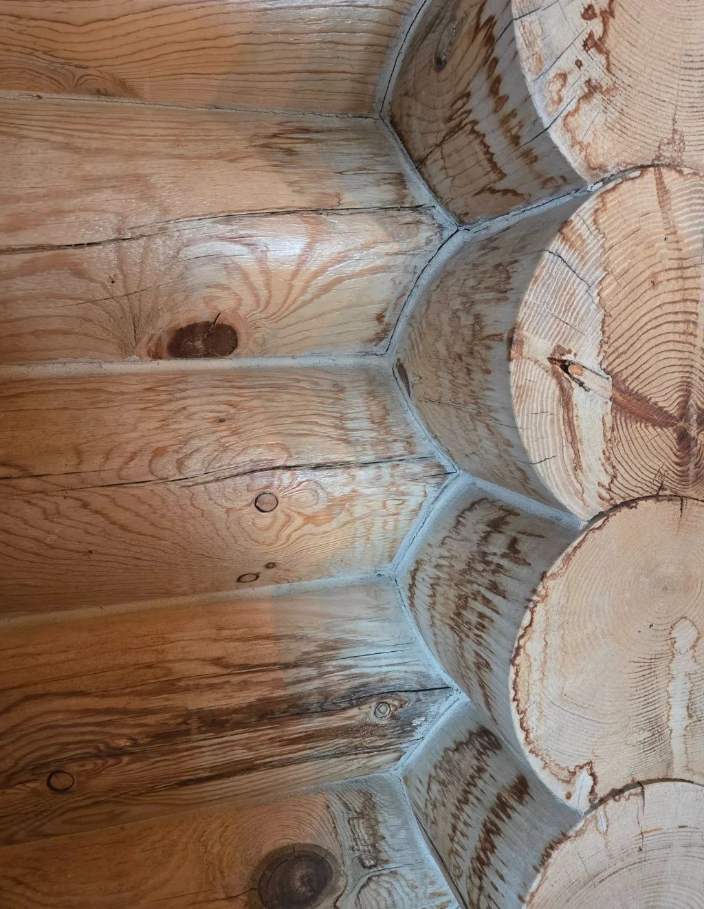 Interior corner of a Swedish cope log home showing dark water stain marks running down between the logs, with visible tannin bleeding at the log joints and corner intersections