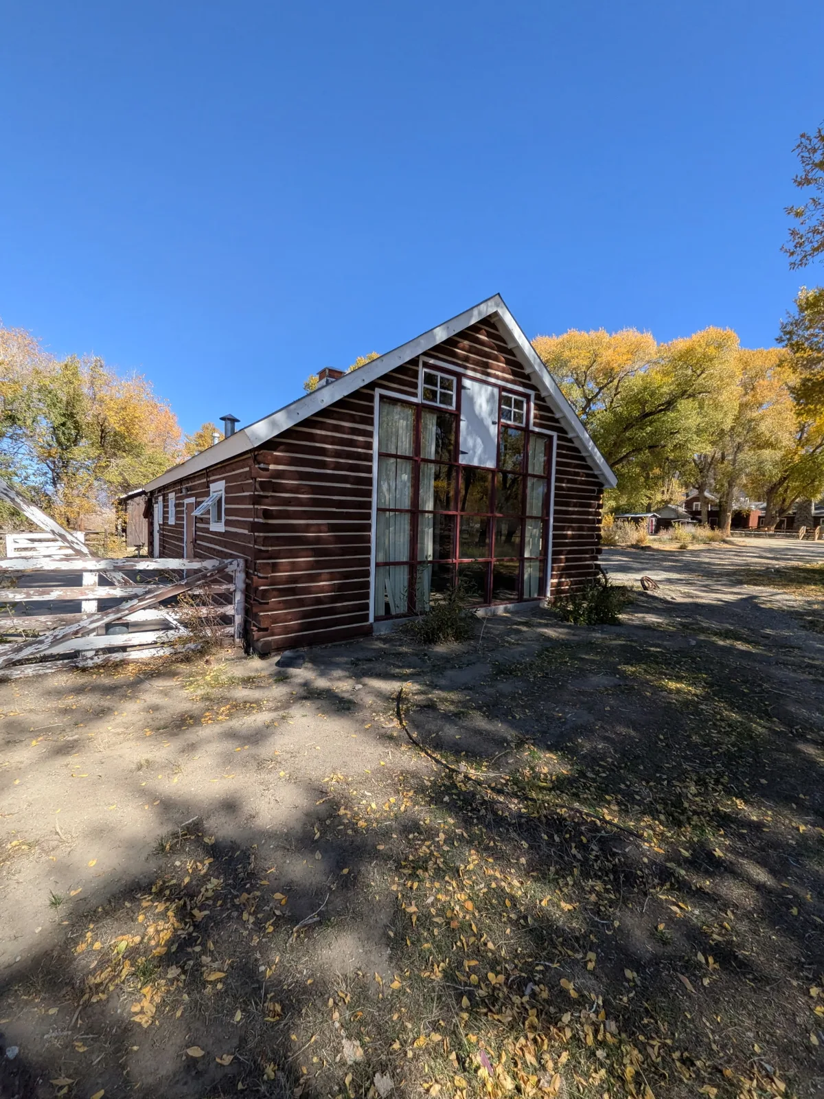 Gabled log building with tall glazed doors and a white fence at Zapata Ranch