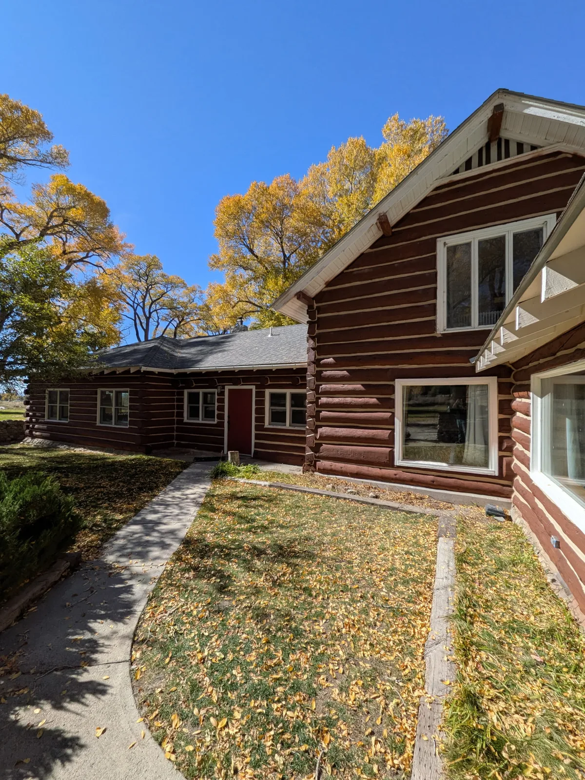 Connected log building elevations with white window trim overlooking a courtyard