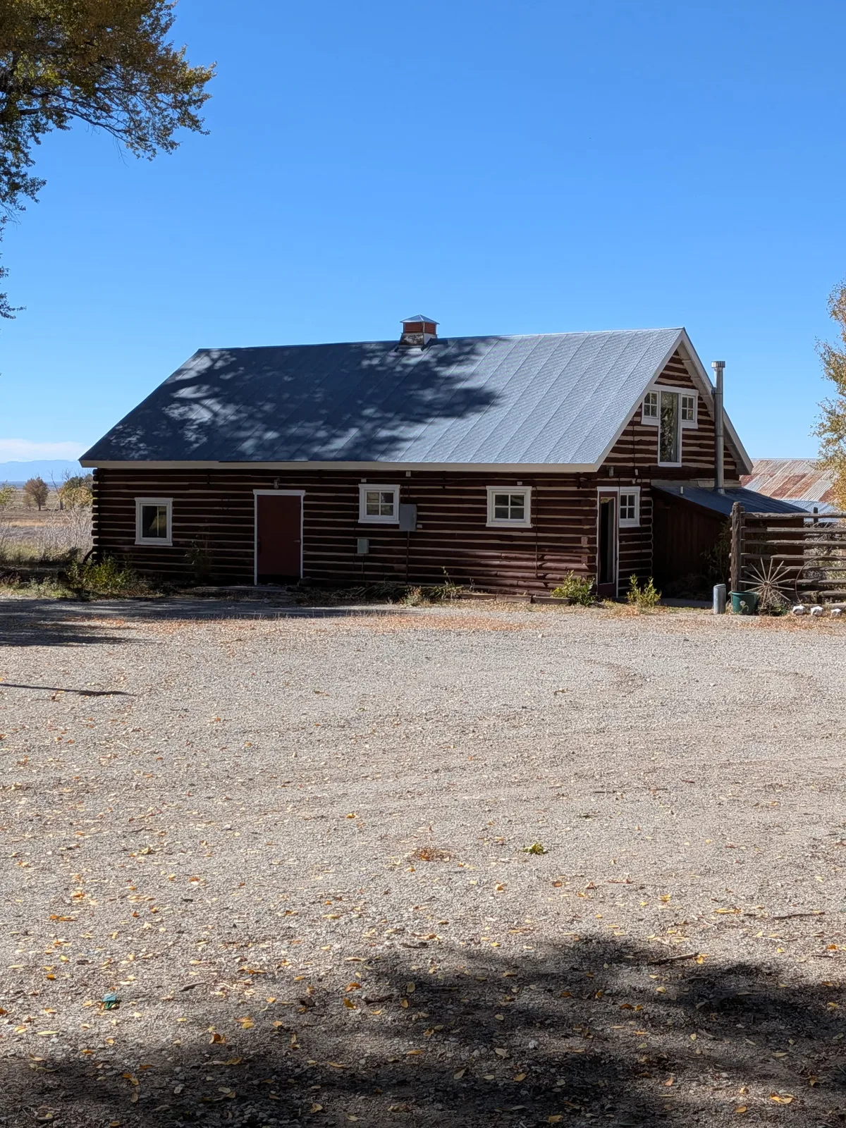 Long log building with a steep metal roof and small white-trimmed windows