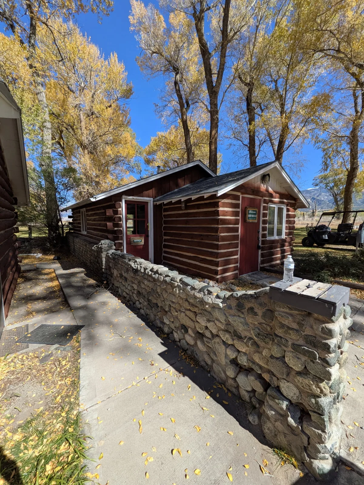 Small log building marked Office behind a stone wall at Zapata Ranch